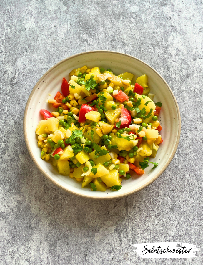 Nahaufnahme eines veganen Kartoffelsalats mit frischer Petersilie, Mais und Erbsen – ideal für Buffet oder Meal Prep.