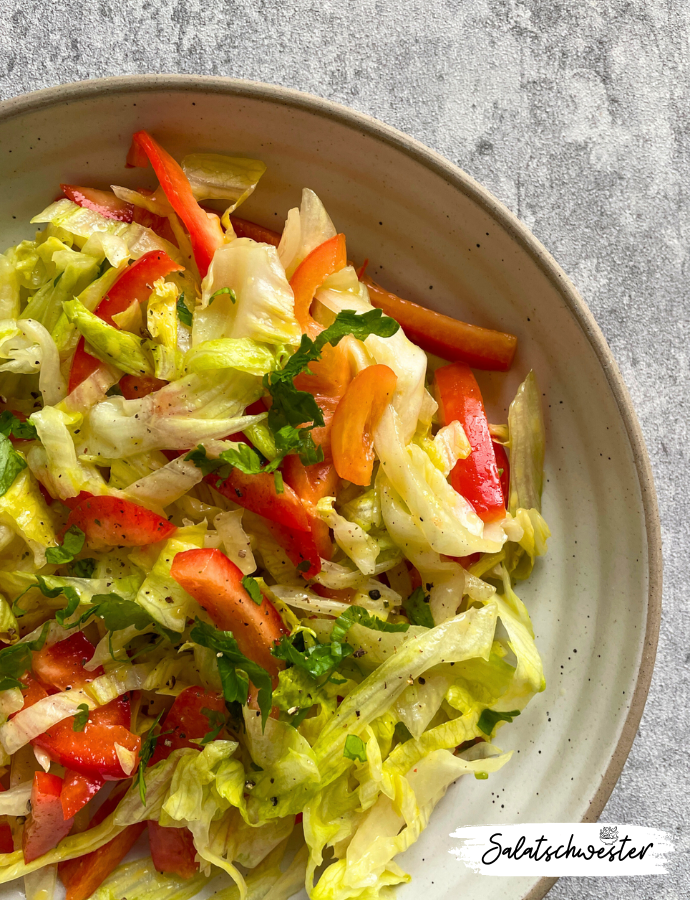 Veganes Salatgericht mit Eisbergsalat, Paprika und hausgemachtem Senfdressing – angerichtet auf einem Esstisch im Freien.