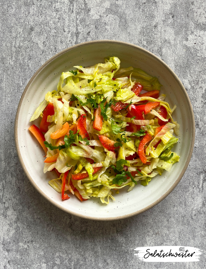 Bunter Paprika-Eisbergsalat mit cremigem Senfdressing in einer weißen Schüssel – frischer, veganer Sommersalat für jede Gelegenheit.
