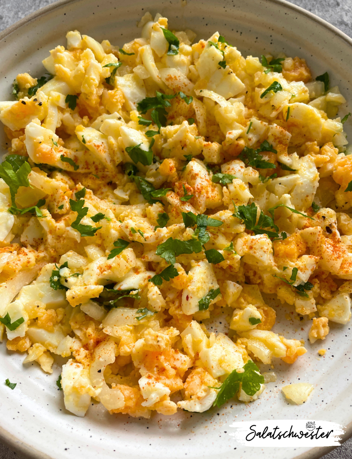 Klassischer Eiersalat mit Zwiebeln und Öl in einer Glasschüssel – einfach und vegetarisch