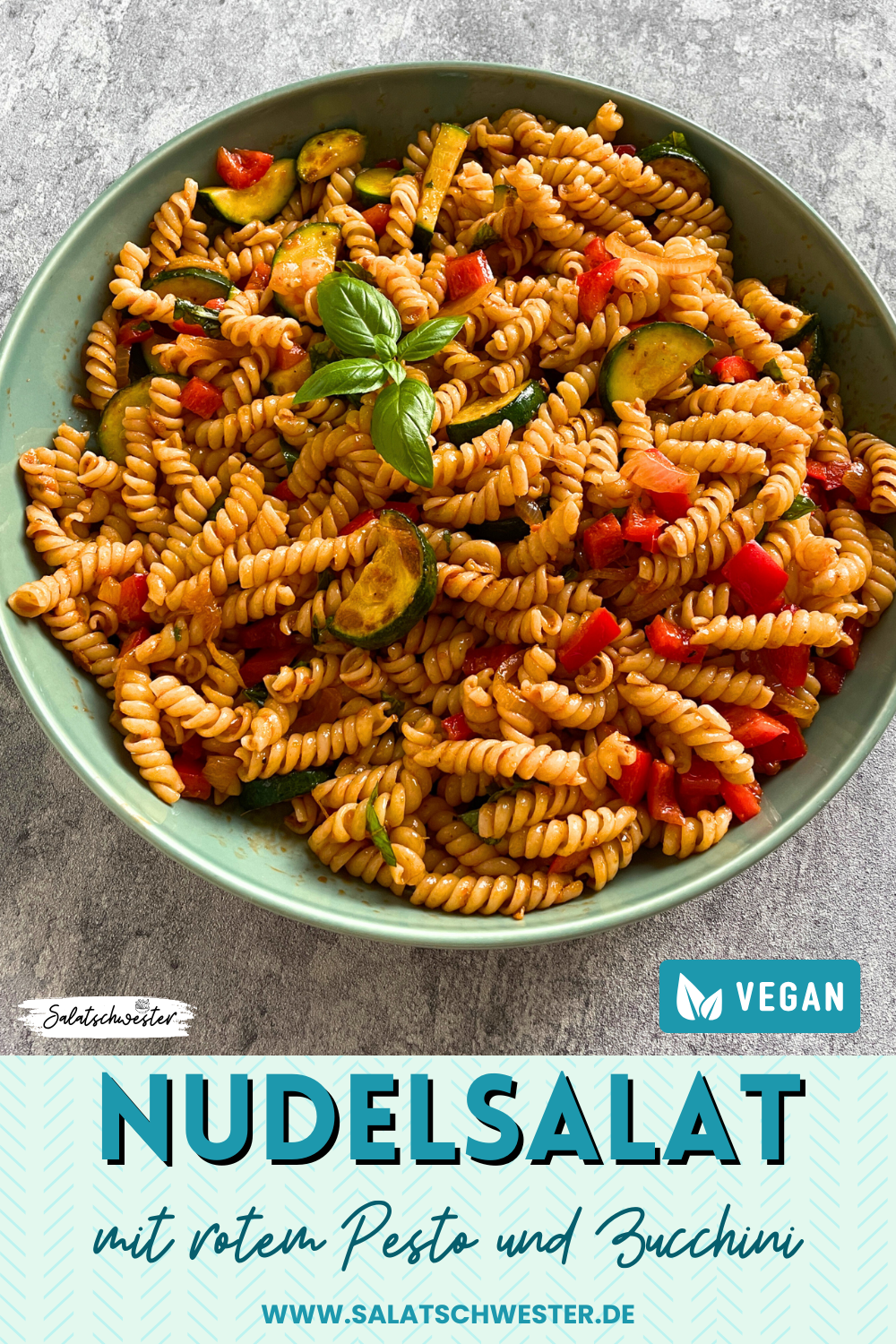 Schüssel mit Nudelsalat, bestehend aus Pasta, gebratenen Zucchinischeiben, Paprika, Pesto Rosso und frischen Basilikumblättern.