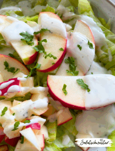 Frisch angerichteter Eisbergsalat mit Apfel und Joghurtdressing in einer weißen Schale – ein leichtes, veganes Gericht für jeden Tag.