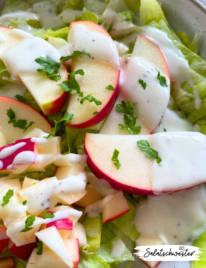 Frisch angerichteter Eisbergsalat mit Apfel und Joghurtdressing in einer weißen Schale – ein leichtes, veganes Gericht für jeden Tag.