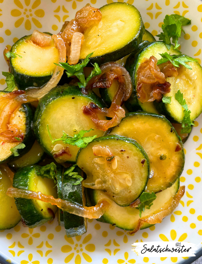 Nahaufnahme von kaltem Zucchinisalat mit Zwiebeln, angerichtet mit frischen Kräutern – vegan, aromatisch und einfach.