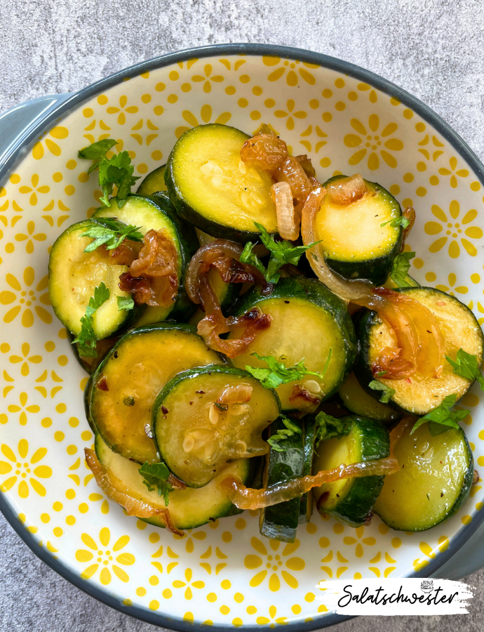 Gebratene Zucchinischeiben treffen auf gebräunte Zwiebeln: ein kalter Zucchinisalat mit Zwiebeln als veganes Highlight für jeden Tag.