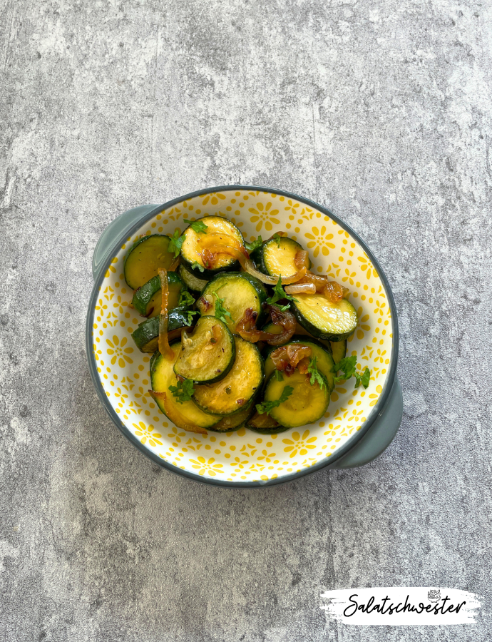 Kalter Zucchinisalat mit Zwiebeln in feinen Scheiben – servierfertig mit leichtem Essig-Öl-Dressing und frischer Petersilie.