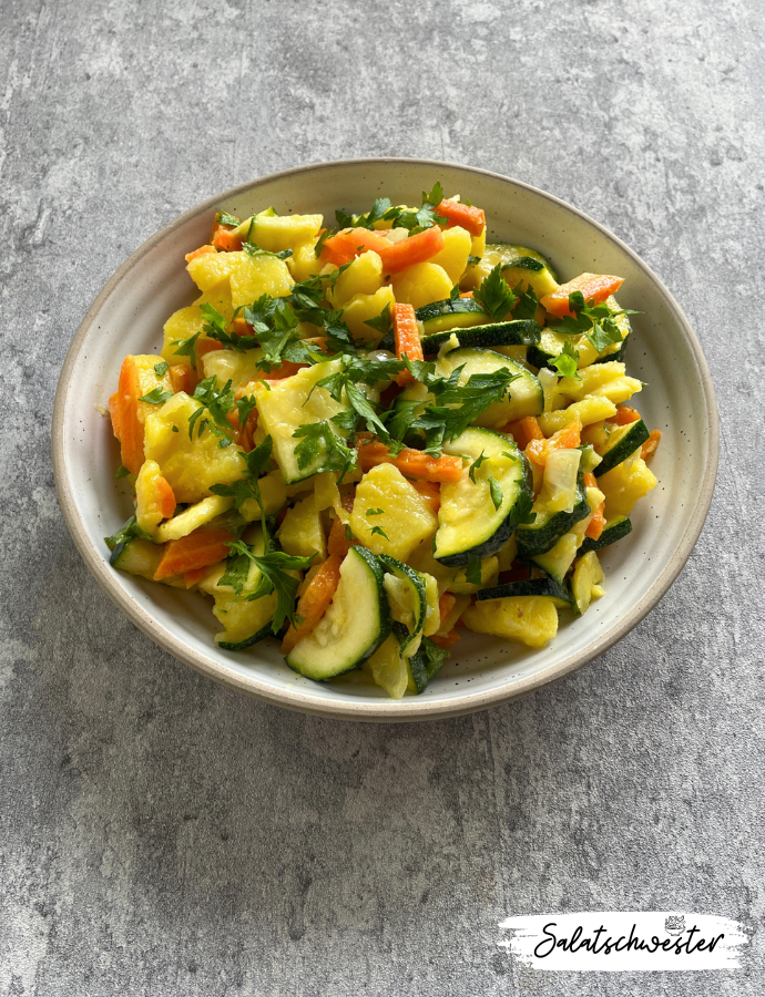 Kartoffelsalat mit Gemüse, angerichtet in einer großen Schüssel für ein Buffet.