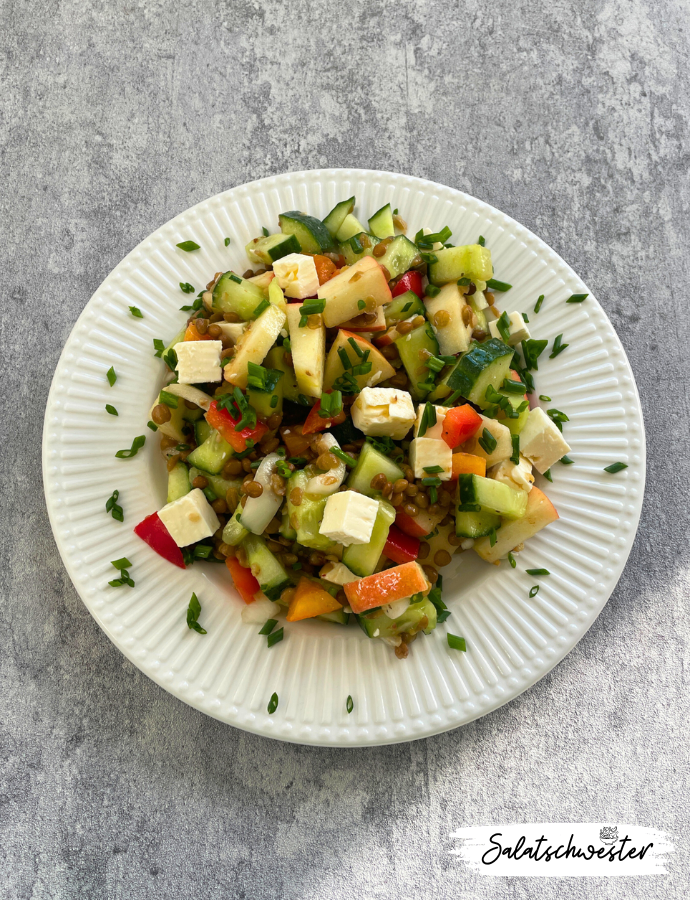 Bunter Linsensalat mit Feta und Apfel in einer Schüssel, serviert mit frischen Kräutern