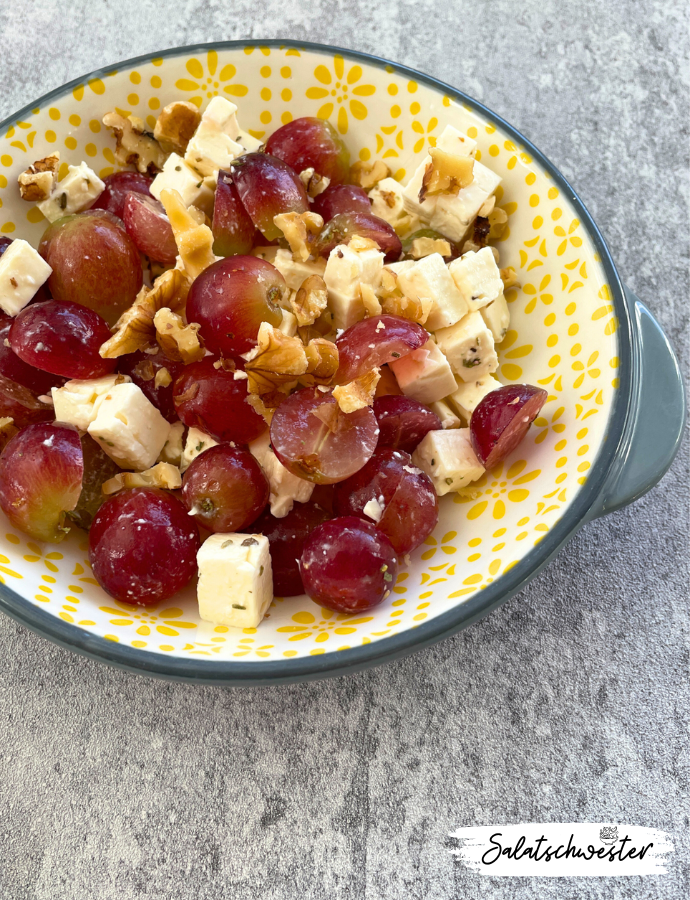 Farbenfroher Trauben-Feta-Salat mit nussigem Topping und frischen Kräutern serviert