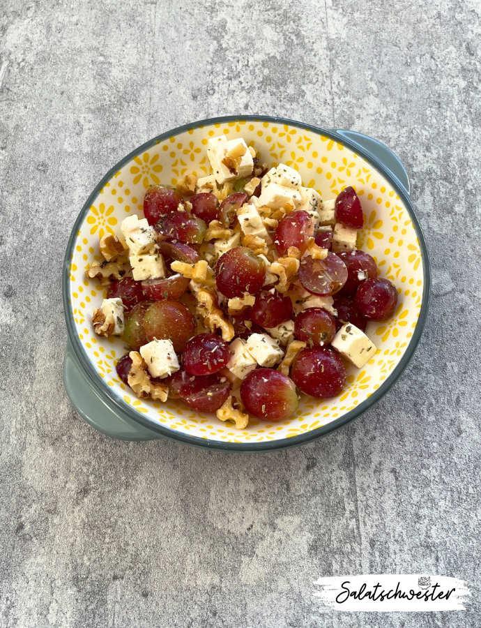 Cremiger Trauben-Feta-Salat mit Walnüssen und Kräutern der Provence dekoriert